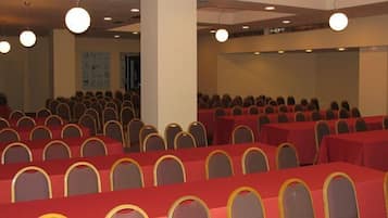 A conference room with rows of tables and chairs, a large pillar, and overhead lighting.