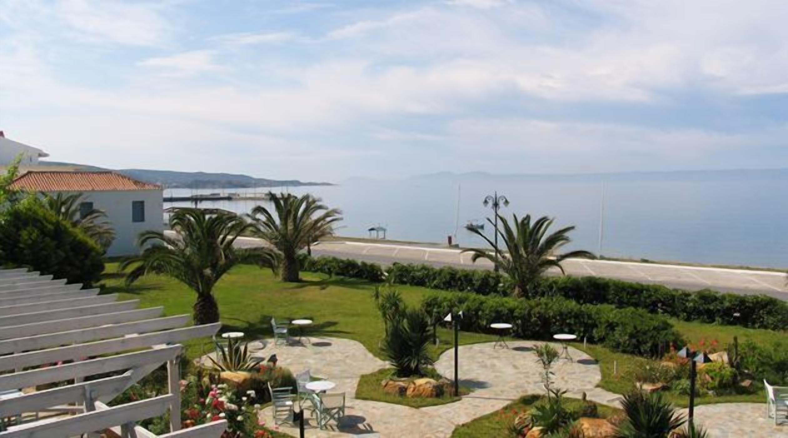 A coastal view with a paved patio, outdoor seating, and a building with a tiled roof.