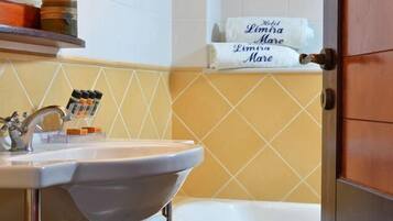 A bathroom with a sink, toiletries, and a towel rack with a sign reading "Hotel Limira Mare".