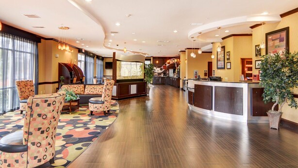 A hotel lobby with a reception desk, seating area with patterned chairs, and a large window with curtains. - Comfort Suites Kilgore (Kilgore)