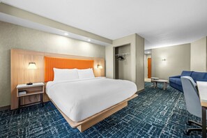 A hotel room with a large bed, a desk, a chair, a wardrobe, and a small table. - Fairfield Inn & Suites by Marriott Gadsden (Gadsden)