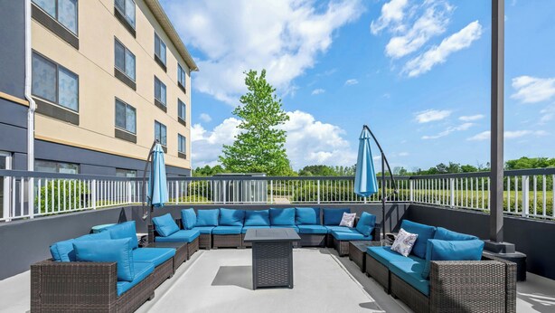 An outdoor seating area with a sectional sofa, a small table, and two umbrellas. - Fairfield Inn & Suites by Marriott Gadsden (Gadsden)