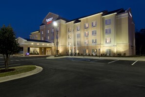 Ett Fairfield Inn & Suites-hotell med en parkeringsplats och en väl upplyst entré.