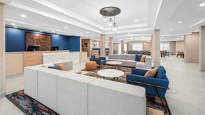 A modern hotel lobby with a reception desk, seating areas, and a dining space. - Fairfield Inn & Suites by Marriott Gadsden (Gadsden)