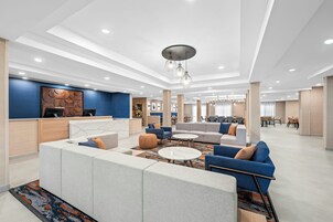 Un moderno vestíbulo de hotel con mostrador de recepción, zonas de estar y un espacio para comer.