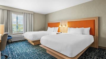 Habitación de hotel con dos camas, un escritorio y una ventana con cortinas.
