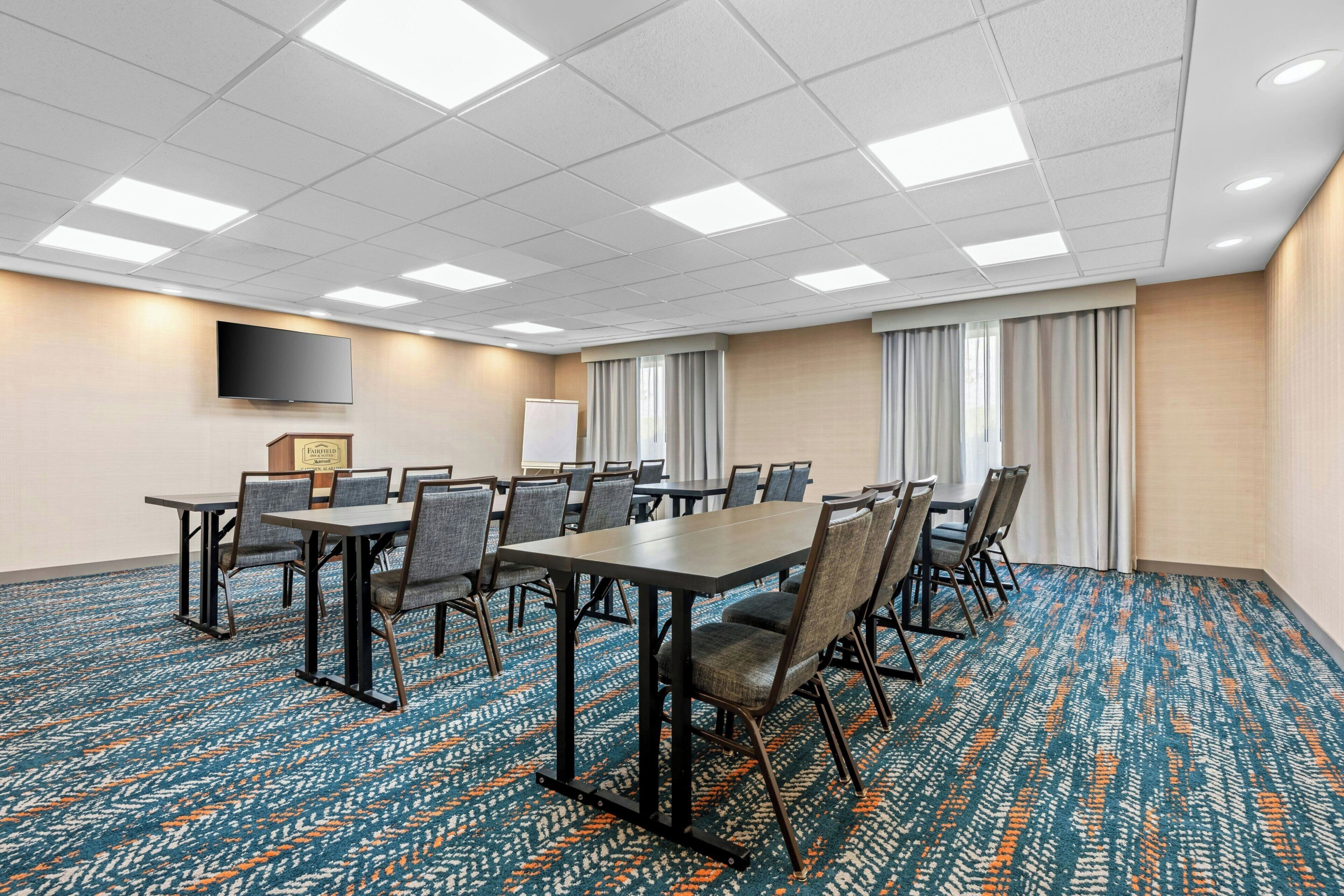 A conference room with a large table, chairs, a flat-screen TV, and a whiteboard.