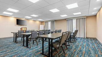 A conference room with a large table, chairs, a flat-screen TV, and a whiteboard.