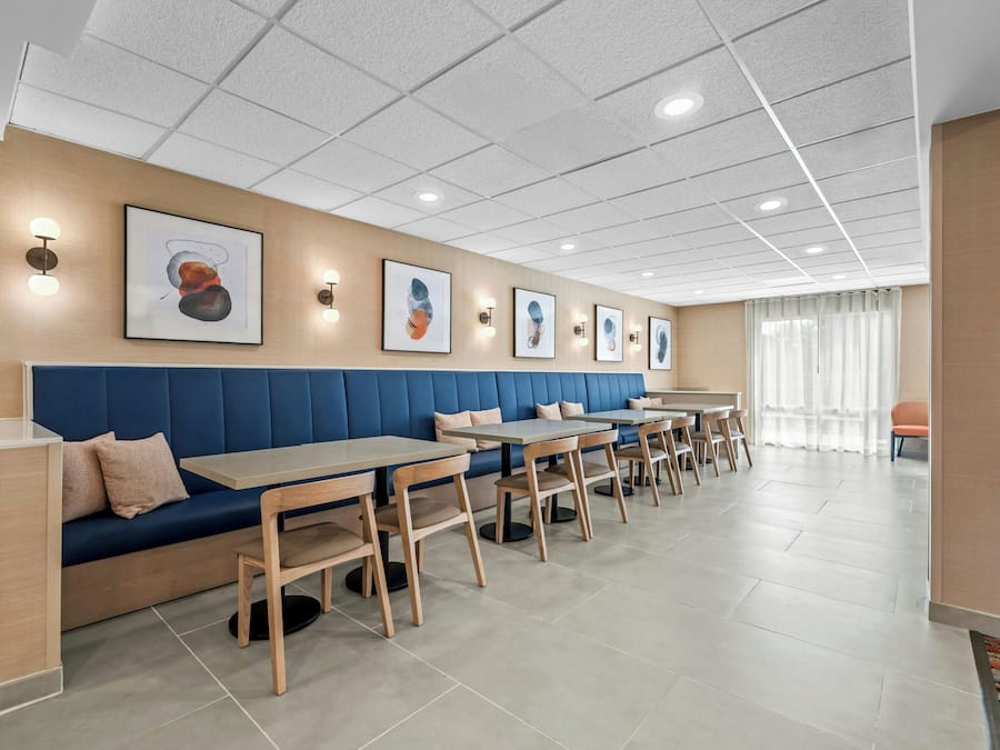 A modern dining area with blue cushioned seating, wooden tables, and artwork on the walls.