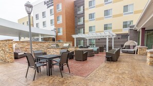 An outdoor patio area with a stone wall, a grill, and outdoor seating. - Fairfield Inn & Suites by Marriott Bartlesville (Bartlesville)