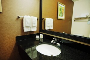 A bathroom with a black granite countertop, a white sink, and a large mirror. - Fairfield Inn & Suites by Marriott Bartlesville (Bartlesville)
