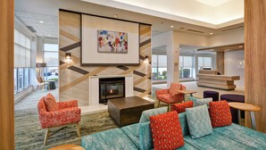 A modern lobby with a fireplace, seating area, and a reception desk. - Hilton Garden Inn Ridgefield Park (Ridgefield Park)