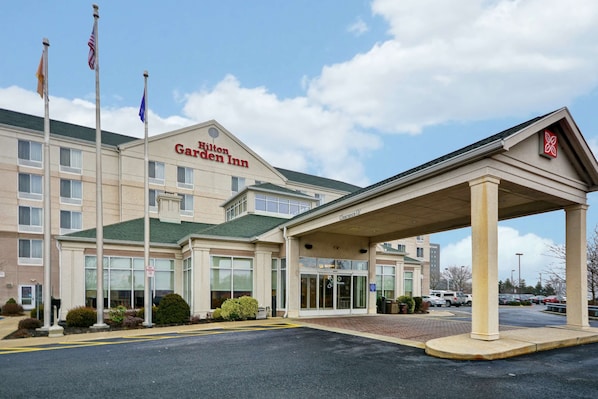 A Hilton Garden Inn with a covered entrance, multiple flags, and a parking lot.