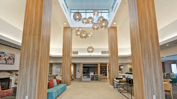 A spacious lobby with high ceilings, a central seating area, and a bar. - Hilton Garden Inn Ridgefield Park (Ridgefield Park)