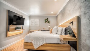 A modern bedroom with a bed, TV, wooden headboard, and a wall-mounted shelf. - The Beverly House by AGA - Beverly Hills (Los Angeles)