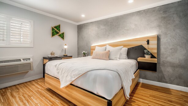 A modern bedroom with a wooden bed, a bedside table, a wall-mounted shelf, and a window with shutters. - The Beverly House by AGA - Beverly Hills (Los Angeles)