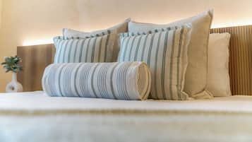 A neatly made bed with striped pillows and a rolled-up blanket.