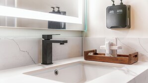 A bathroom with a white sink, black faucet, and a soap dispenser on the wall. - The Beverly House by AGA - Beverly Hills (Los Angeles)