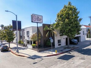 A building with a sign for 'The Beverly House' hotel, a palm tree, and a parked car.