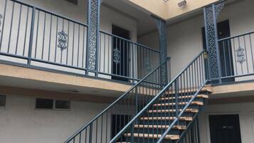 A multi-level building with a central staircase, balconies with decorative railings, and a flat roof.