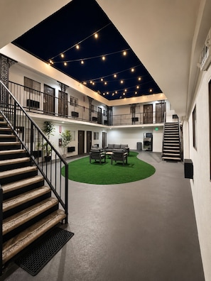 A spacious indoor area with a central seating area, a staircase, and a balcony with string lights. - The Beverly House by AGA - Beverly Hills (Los Angeles)