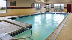 Una piscina interior con agua cristalina azul, paredes enlosadas y un letrero de salvavidas.