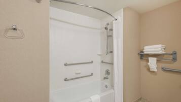 A bathroom with a bathtub, grab bars, a towel rack, and a shower curtain.