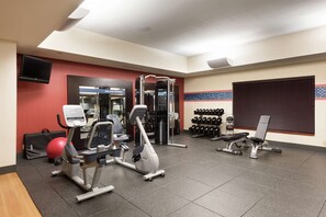 A gym with exercise equipment, a television, and a wall-mounted dumbbell rack. - Hampton Inn Branson - Branson Hills (Branson)