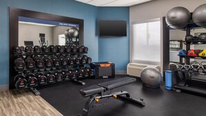 Ein Fitnessraum mit Trainingsgeräten, einer Bank und einem Spiegel.