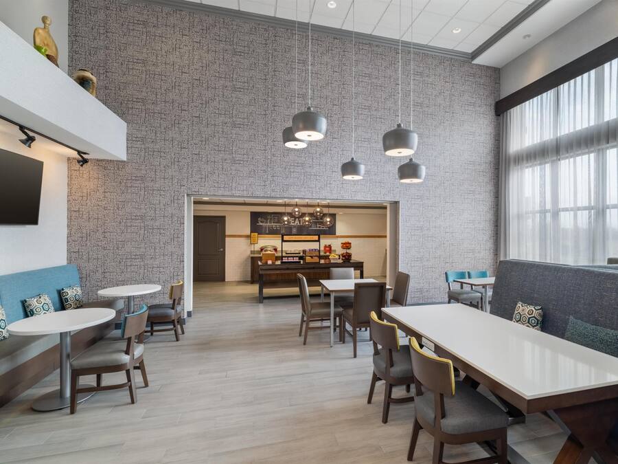 A modern dining area with a brick wall, pendant lighting, and a view of a kitchen area.
