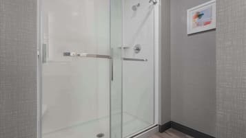 A glass-enclosed shower with a metal handle and a wall-mounted towel rack.