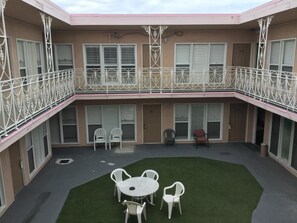 Un edificio di due piani con un cortile coperto, posti a sedere all'aperto e un balcone con ringhiere decorative.