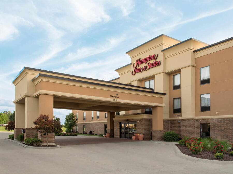 Um Hampton Inn & Suites com entrada acessível, área de espera coberta e fachada de tijolos.