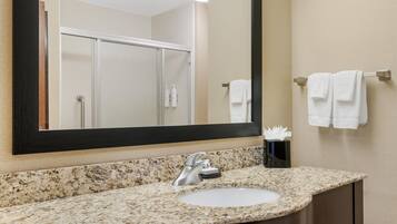 A bathroom with a granite countertop, a sink, a mirror, and a towel rack with towels.