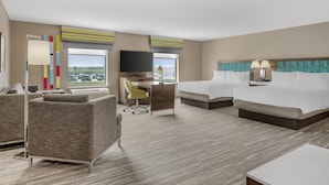 A hotel room with a bed, desk, chair, and a TV.