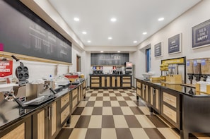 A modern kitchen with checkered flooring, stainless steel appliances, and a chalkboard wall with motivational writing. - Hampton Inn & Suites Crawfordsville (Crawfordsville)