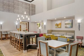 Un comedor moderno con varias mesas y sillas, una isla central y obras de arte en las paredes.