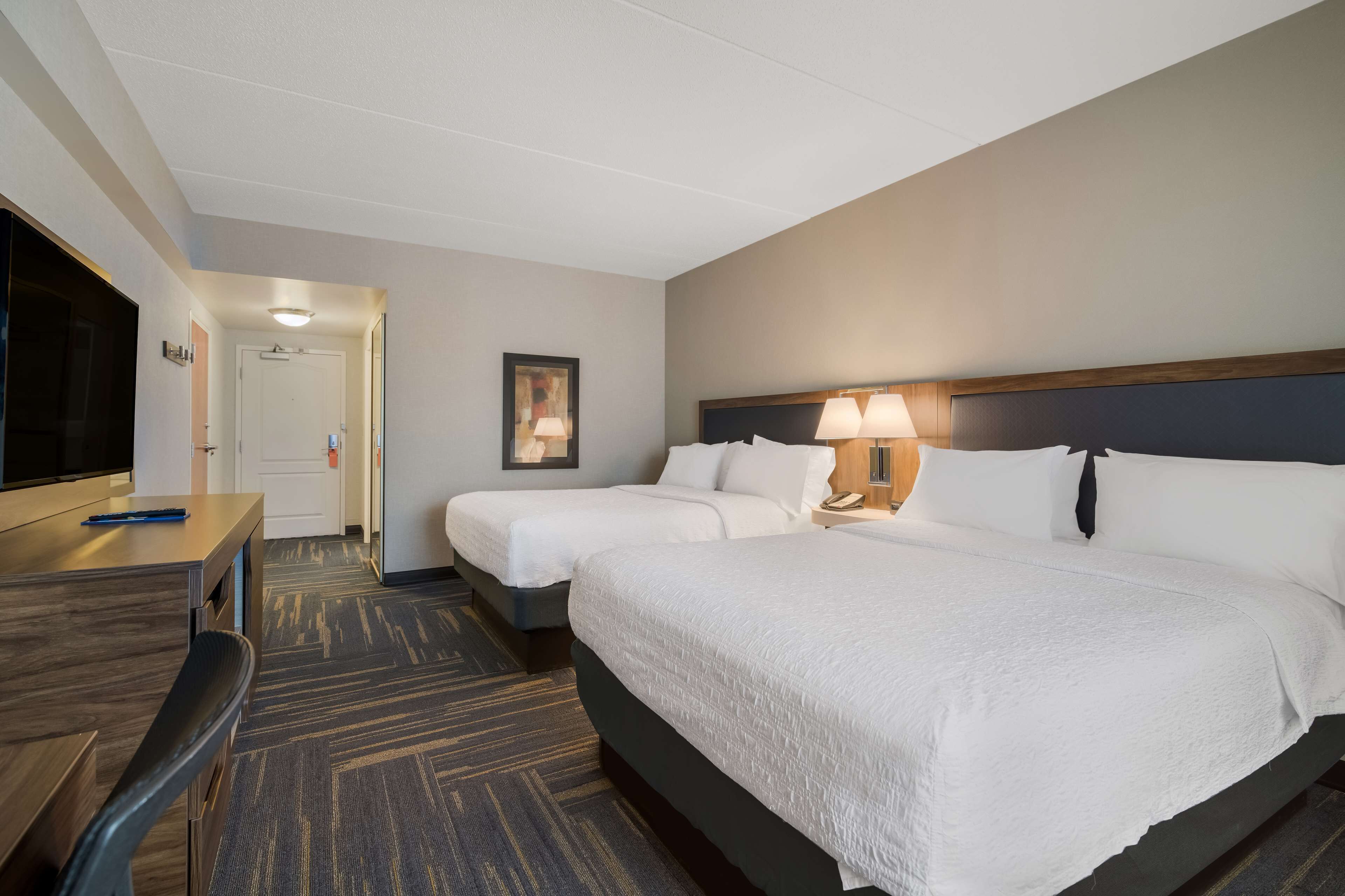 Une chambre d’hôtel avec deux lits, un bureau, une chaise et un téléviseur.