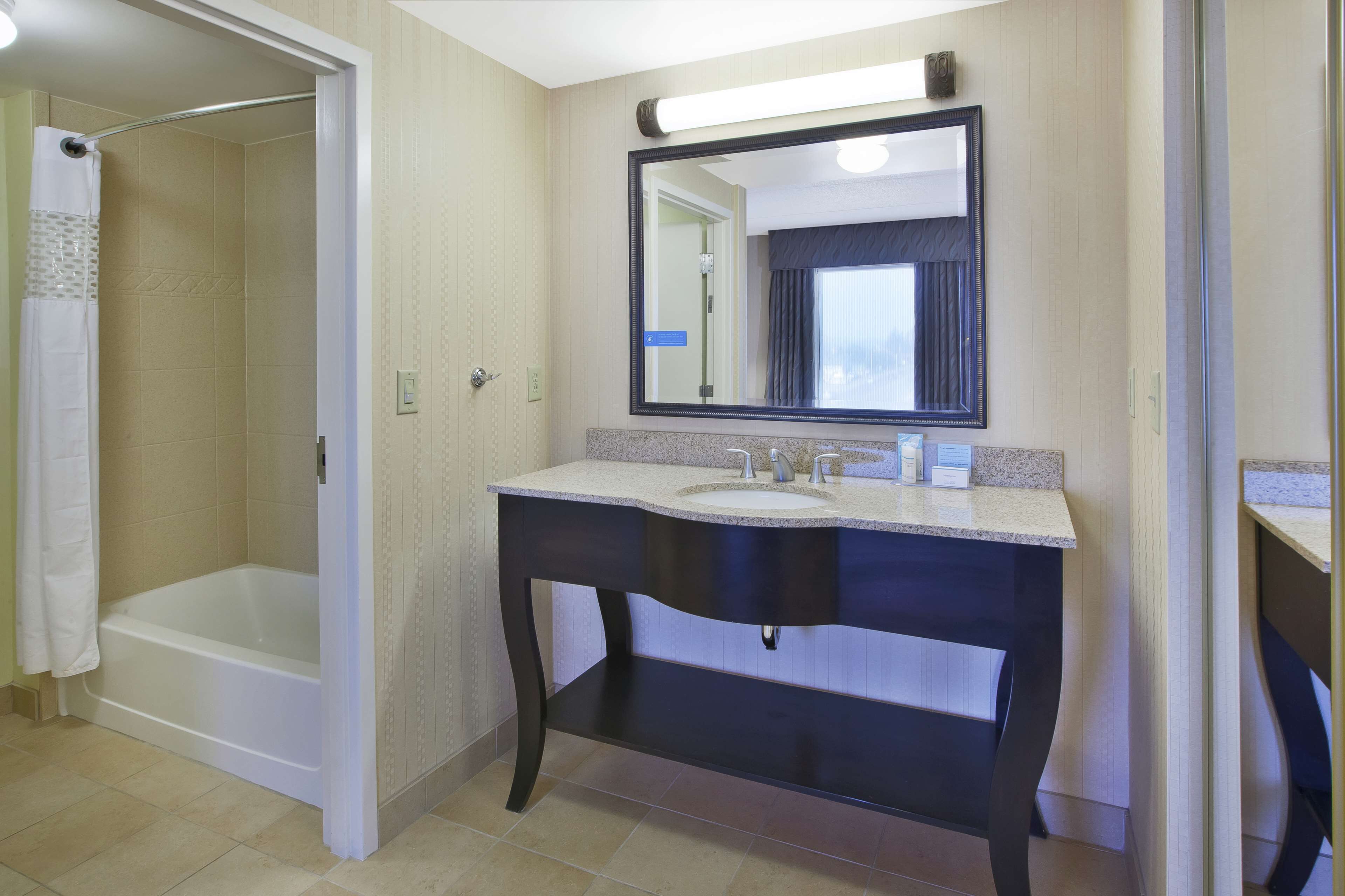 A bathroom with a bathtub, a sink, and a mirror.