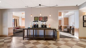 A modern hotel lobby with a checkered floor, a coffee station, and a seating area with a sofa and armchairs. - Hampton Inn & Suites Plattsburgh (Plattsburgh)