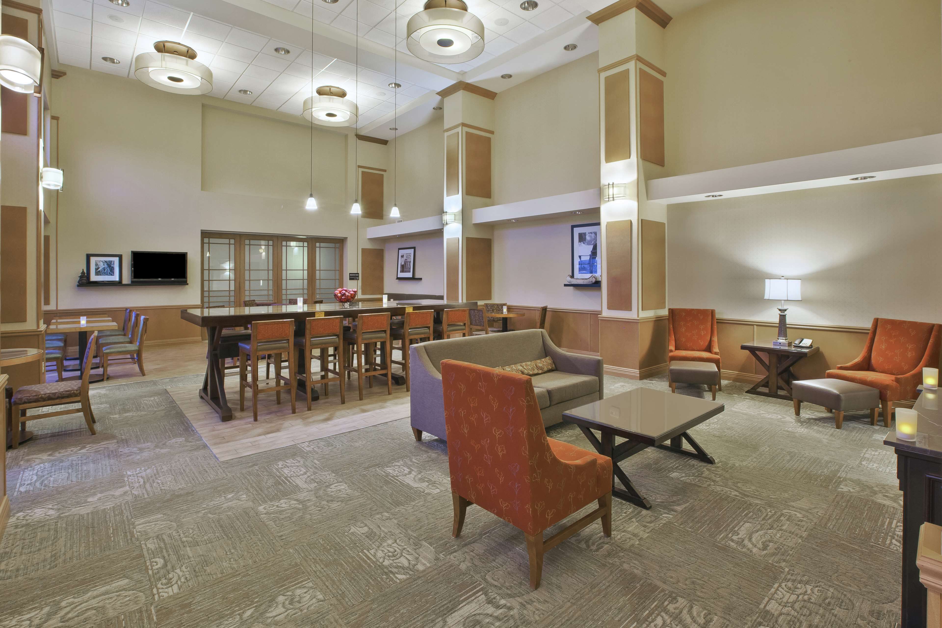 A hotel lobby with a bar area, seating arrangements, and a television.