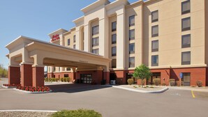 A hotel with a covered entrance, a clear sky, and a parking lot.