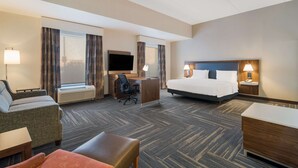 A hotel room with a bed, a desk with a chair, a sofa, and a small table.