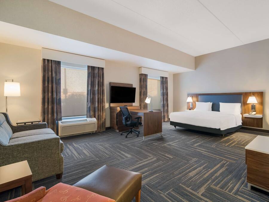 Une chambre d’hôtel comprenant un lit, un bureau avec une chaise, un canapé et une petite table.