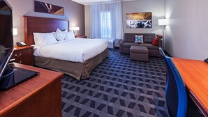 Une chambre d’hôtel avec un grand lit, un bureau, une chaise, un canapé et un téléviseur.