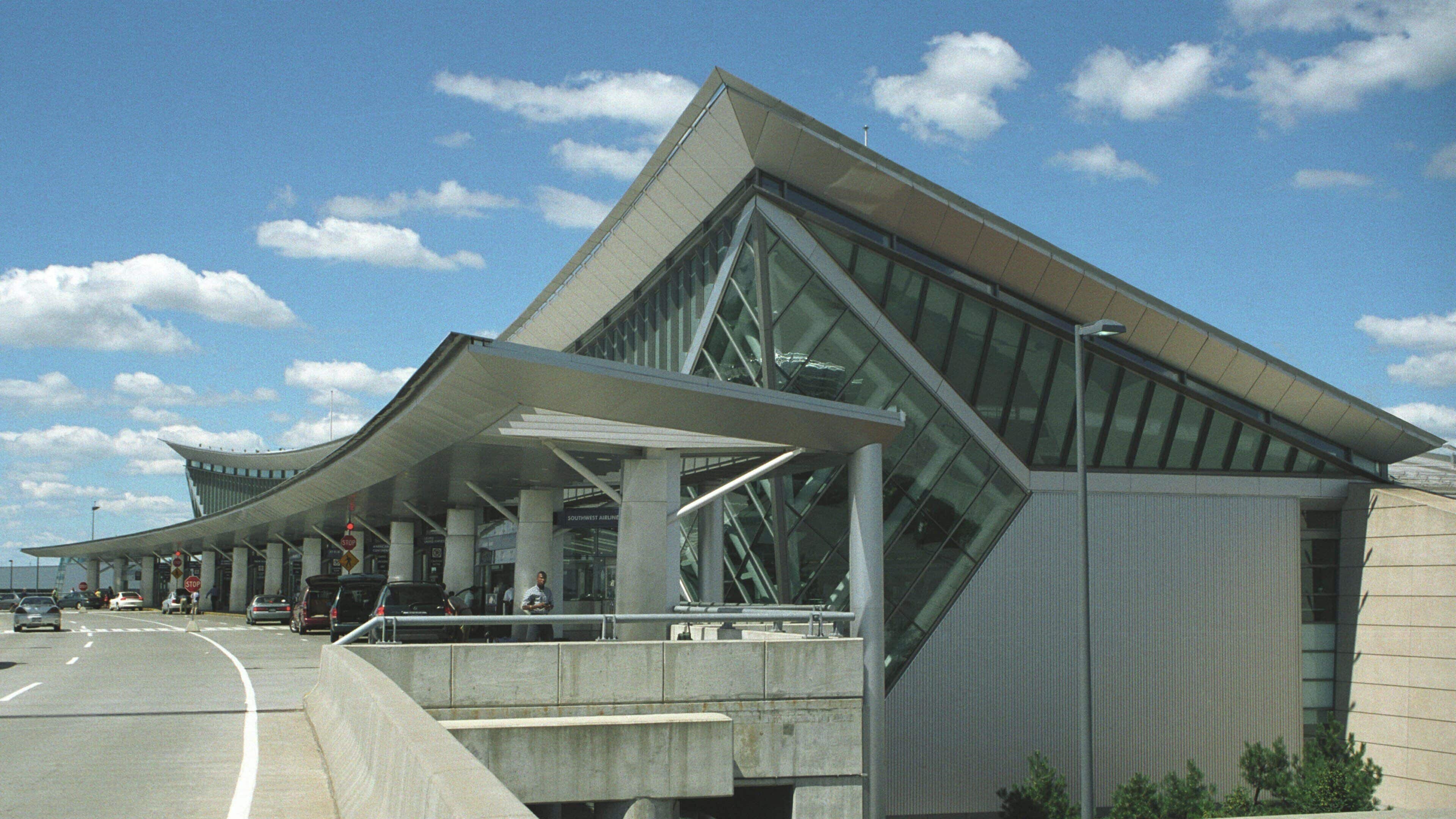 A modern building with a unique angular design, featuring large glass windows and a covered walkway.