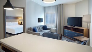 Une chambre d’hôtel avec un lit, un canapé, une télévision, un bureau et une lampe.