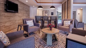 Un espace de détente moderne avec des canapés, une table ronde et un téléviseur à écran plat fixé à un mur en bois.