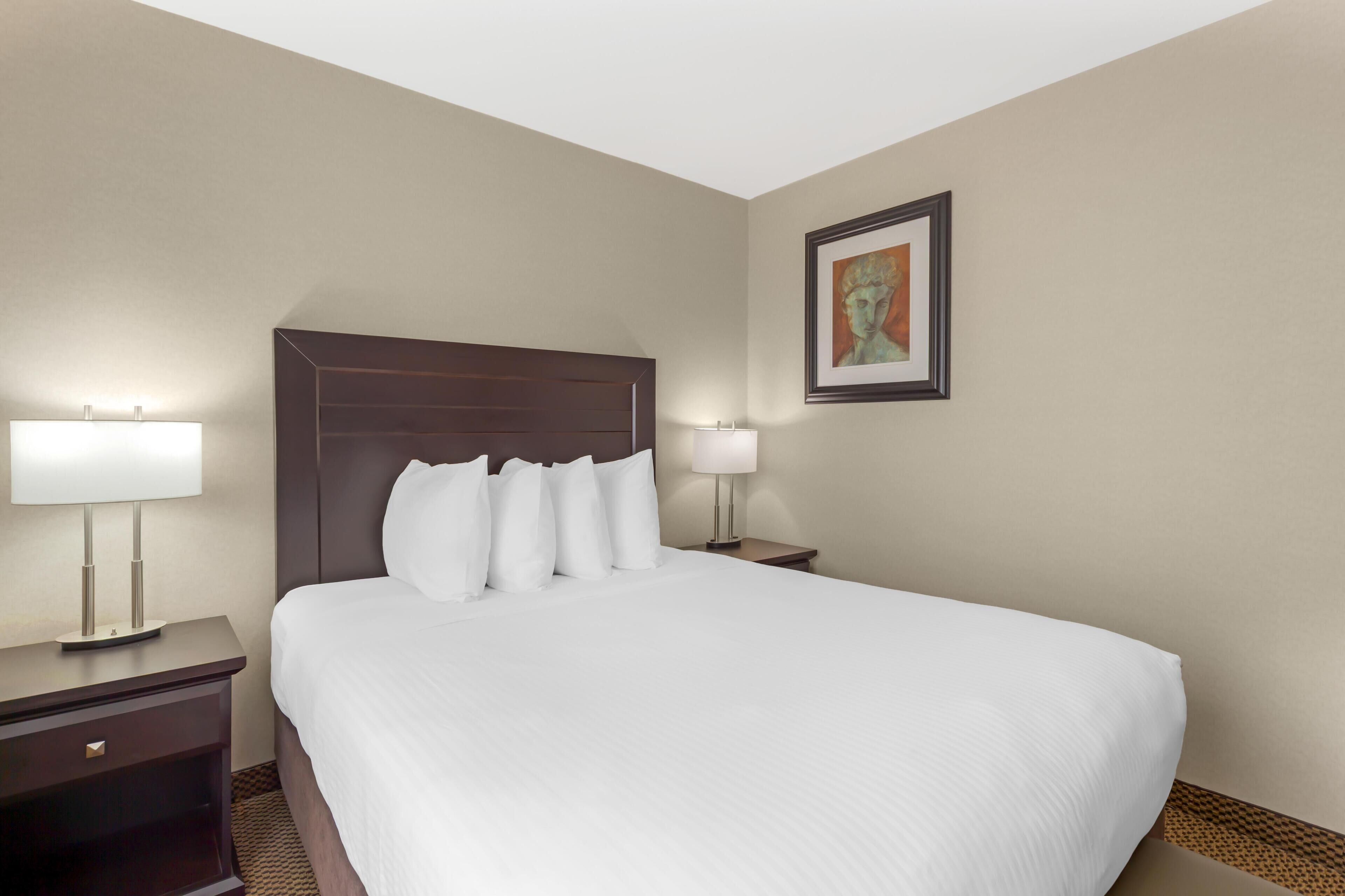A hotel room with a large bed, two bedside tables, and a painting on the wall.