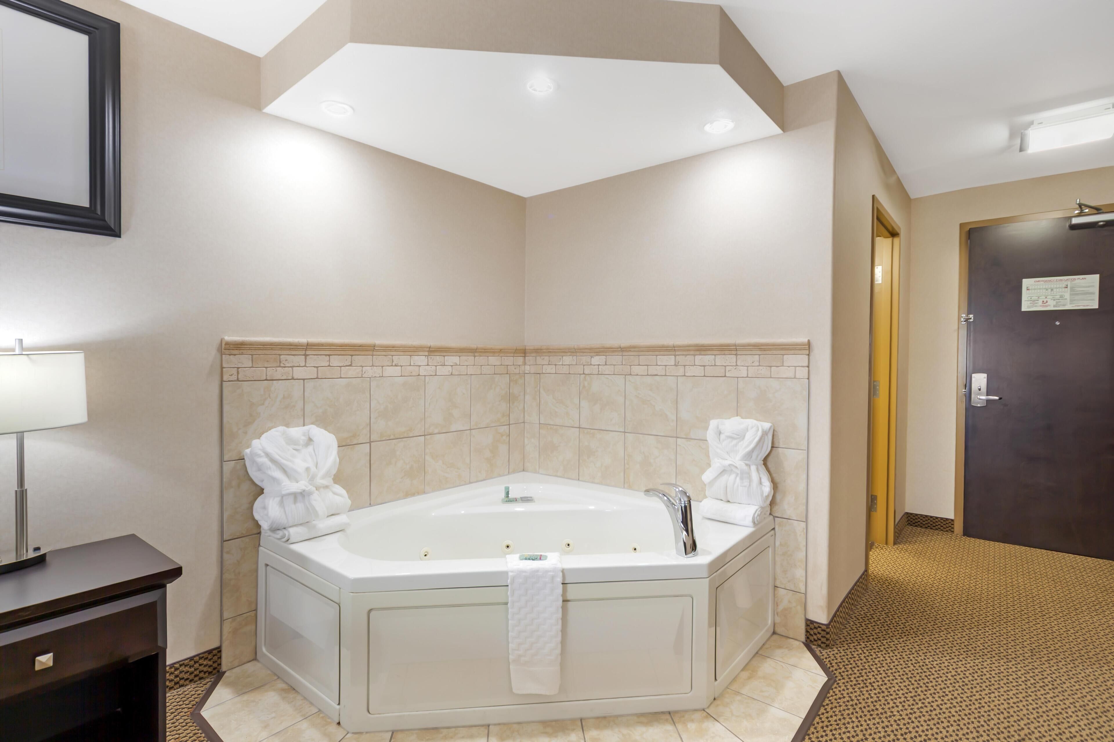 A modern bathroom with a freestanding bathtub, a towel rack, and a door with a sign.